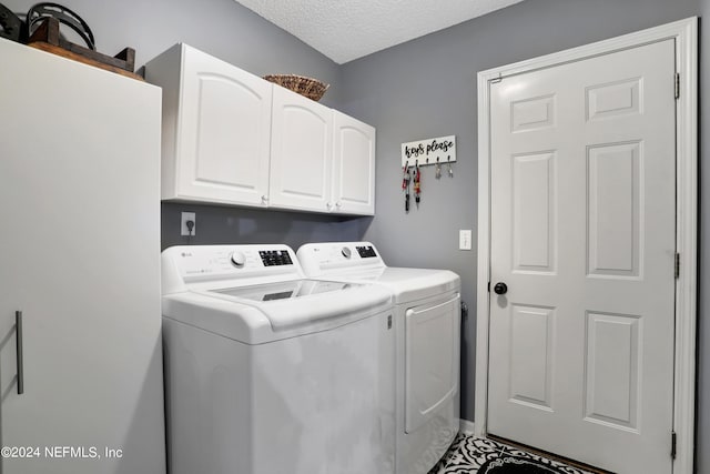 washroom featuring a textured ceiling, cabinets, and separate washer and dryer