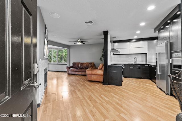 kitchen with sink, decorative backsplash, ceiling fan, appliances with stainless steel finishes, and light hardwood / wood-style floors