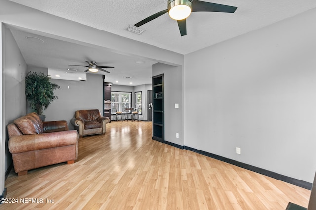 living room featuring a textured ceiling, light hardwood / wood-style flooring, and ceiling fan