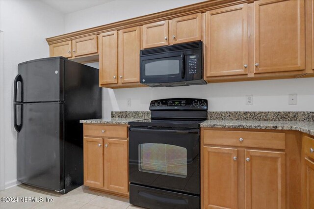 kitchen featuring black appliances, light tile patterned flooring, and light stone countertops