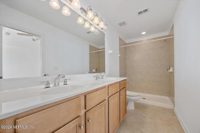 bathroom featuring a tile shower, vanity, toilet, and tile patterned floors