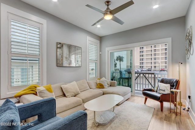 living room featuring a wealth of natural light, light wood-type flooring, and ceiling fan