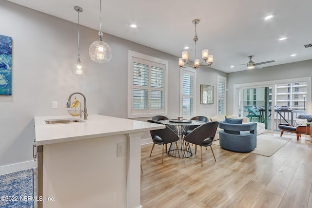 interior space featuring sink, ceiling fan with notable chandelier, light wood-type flooring, and a wealth of natural light