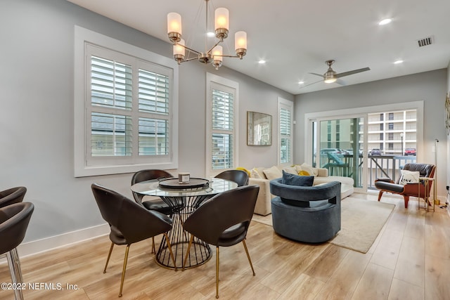 dining room with light hardwood / wood-style flooring and ceiling fan with notable chandelier