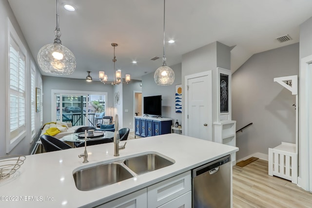 kitchen featuring hanging light fixtures, stainless steel dishwasher, sink, light hardwood / wood-style floors, and blue cabinets