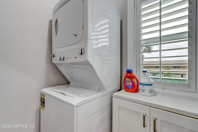 laundry room featuring stacked washer / dryer and cabinets