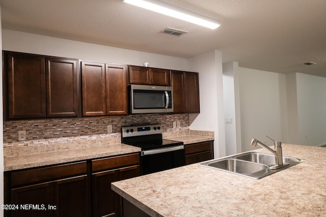 kitchen featuring appliances with stainless steel finishes, dark brown cabinetry, decorative backsplash, and sink