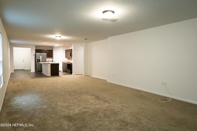 unfurnished living room featuring a textured ceiling and carpet flooring