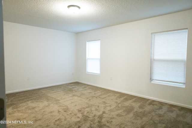 carpeted spare room with a textured ceiling