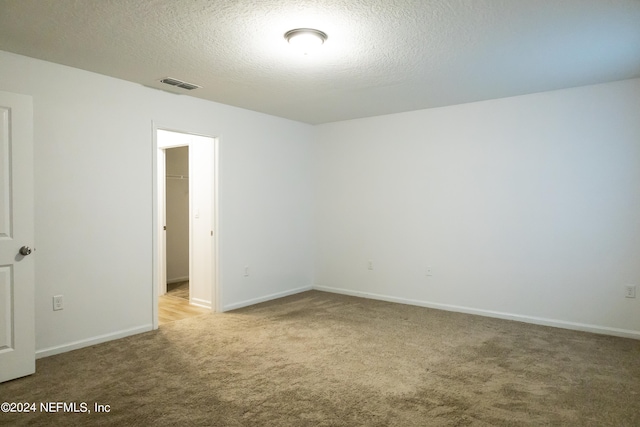 carpeted spare room with a textured ceiling