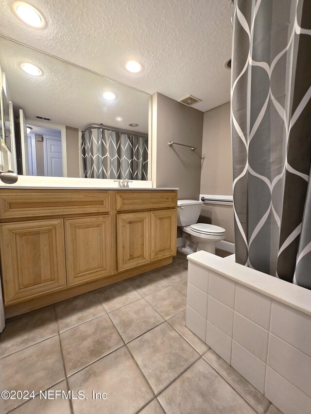 bathroom featuring toilet, walk in shower, tile patterned flooring, vanity, and a textured ceiling