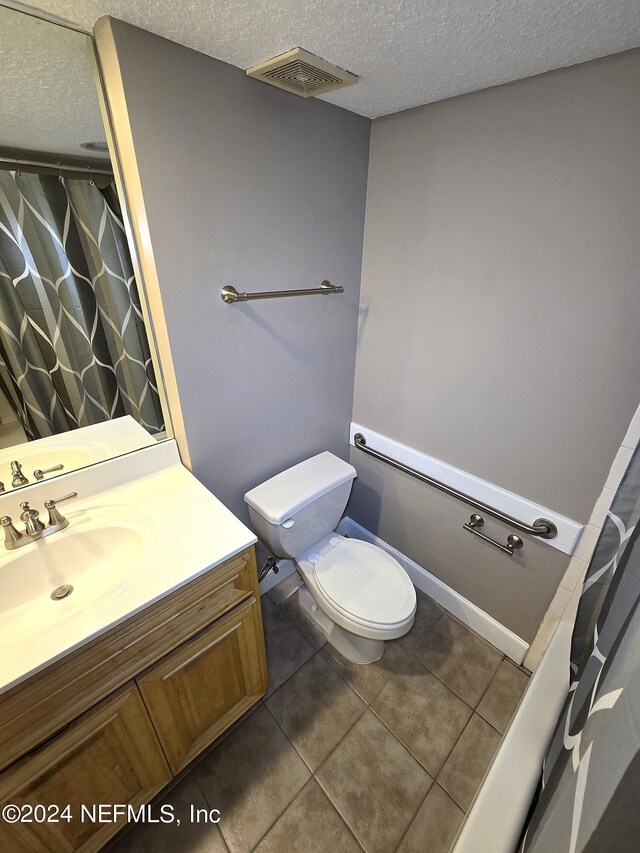 bathroom with vanity, toilet, a textured ceiling, and tile patterned flooring