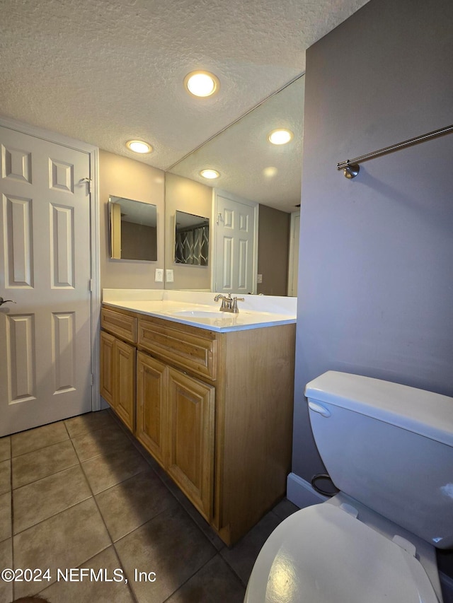 bathroom featuring tile patterned floors, toilet, a textured ceiling, and vanity