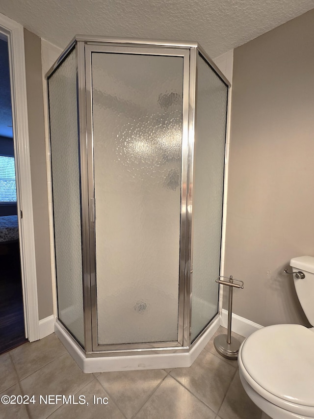 bathroom featuring toilet, a shower with shower door, and tile patterned floors