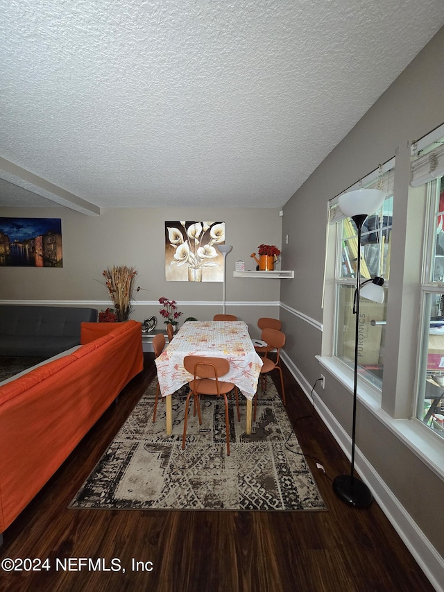 dining area with a textured ceiling and dark wood-type flooring