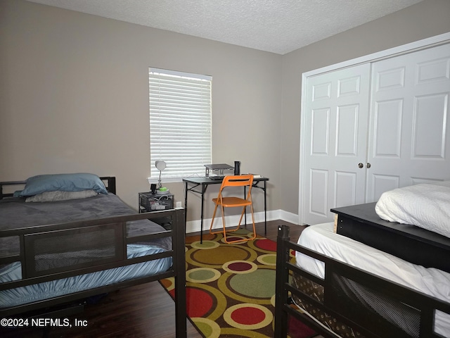 bedroom with a textured ceiling, dark hardwood / wood-style flooring, and a closet