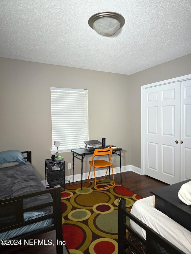 bedroom with a closet, dark hardwood / wood-style floors, and a textured ceiling