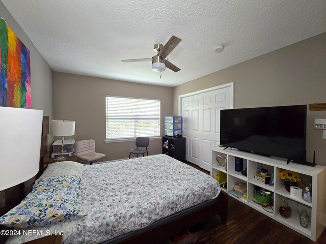 bedroom featuring a textured ceiling, dark hardwood / wood-style flooring, ceiling fan, and a closet