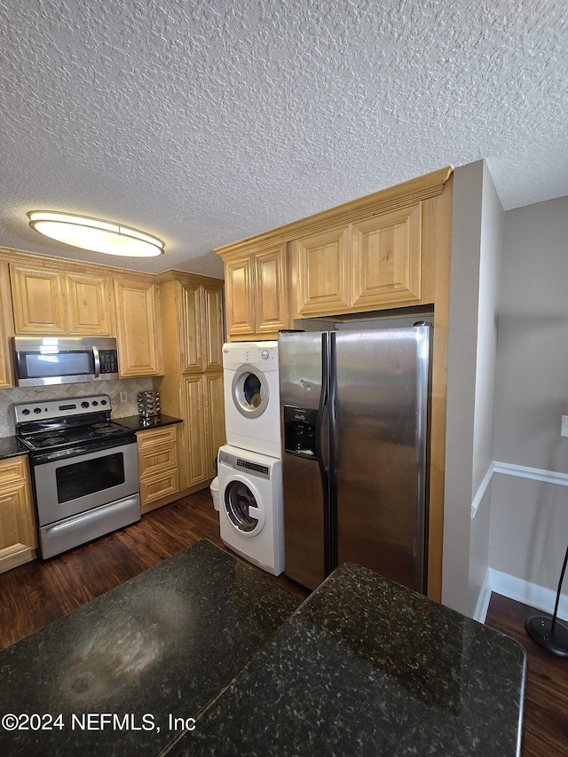 kitchen featuring a textured ceiling, dark wood-type flooring, stainless steel appliances, and stacked washer / dryer