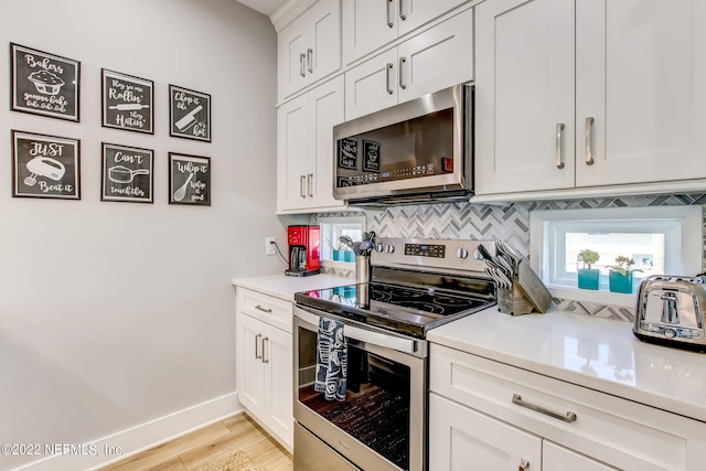 kitchen featuring white cabinets, stainless steel appliances, light hardwood / wood-style floors, and tasteful backsplash