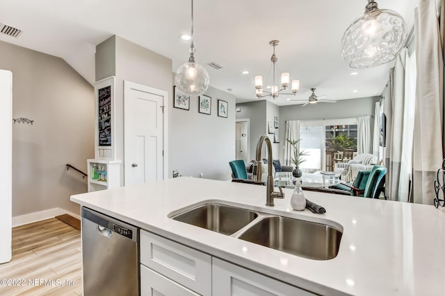 kitchen featuring white cabinets, hanging light fixtures, light wood-type flooring, sink, and stainless steel dishwasher