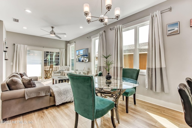 living room with light wood-type flooring, ceiling fan with notable chandelier, and plenty of natural light