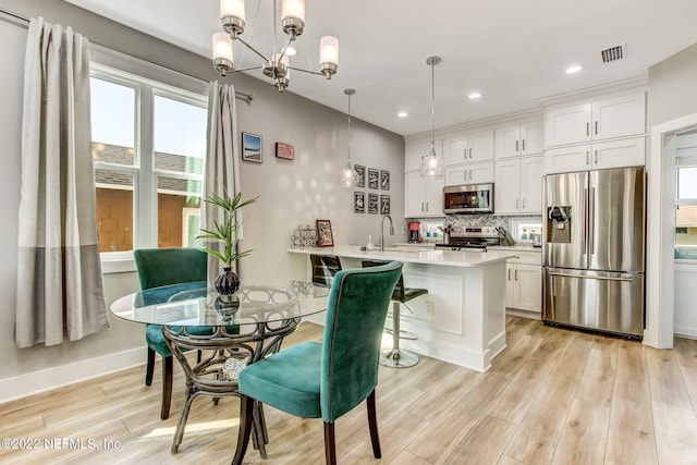 dining room with a wealth of natural light, an inviting chandelier, sink, and light hardwood / wood-style floors