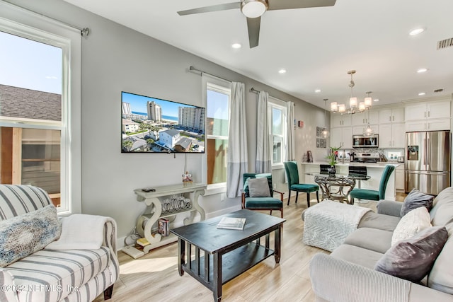 living room featuring ceiling fan with notable chandelier, plenty of natural light, and light hardwood / wood-style flooring