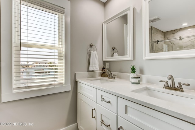 bathroom featuring tiled shower, vanity, and a healthy amount of sunlight