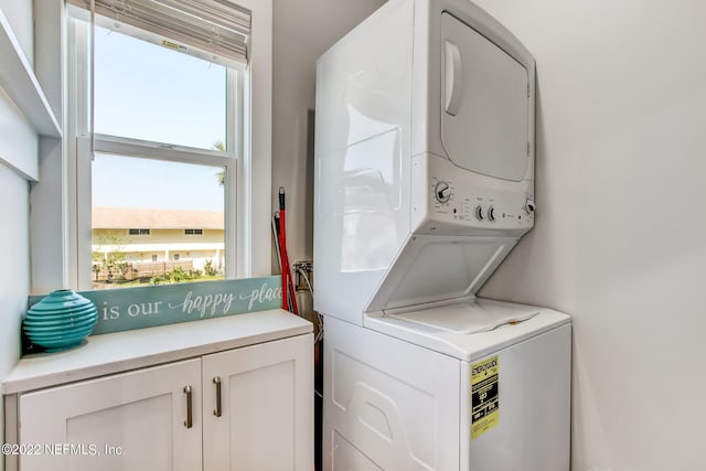 laundry area featuring cabinets and stacked washing maching and dryer