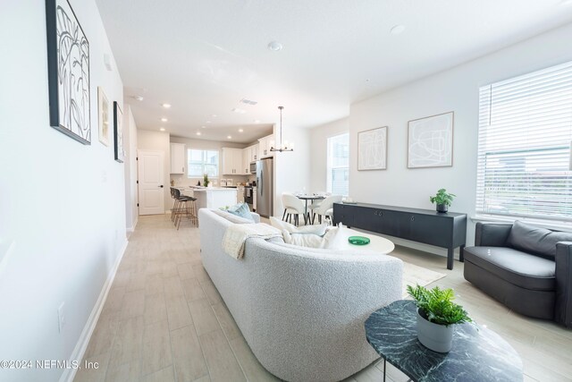 living room with light wood-type flooring and an inviting chandelier