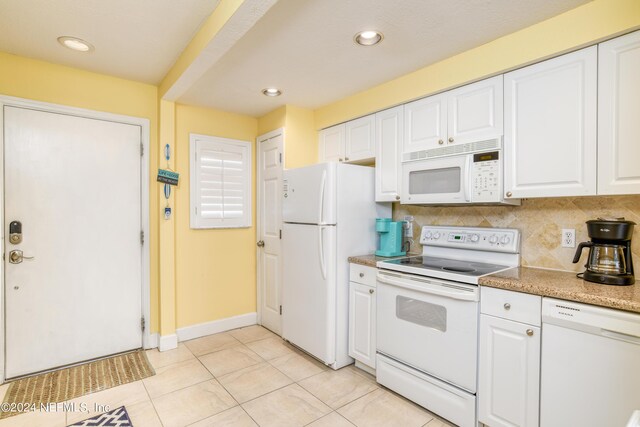 kitchen with white appliances, light tile patterned floors, white cabinets, and tasteful backsplash