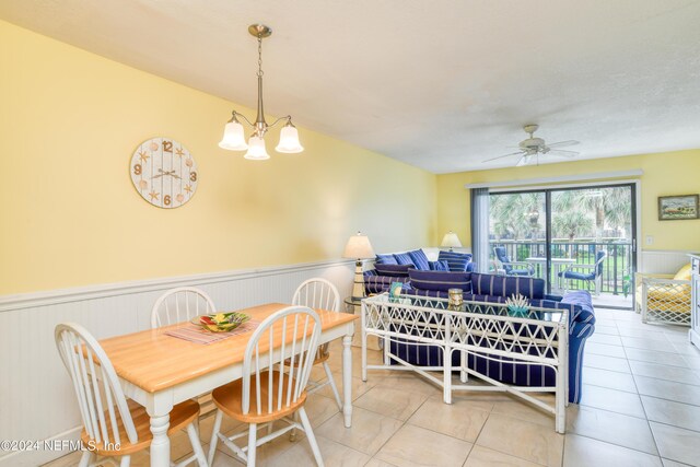 tiled dining area with ceiling fan with notable chandelier