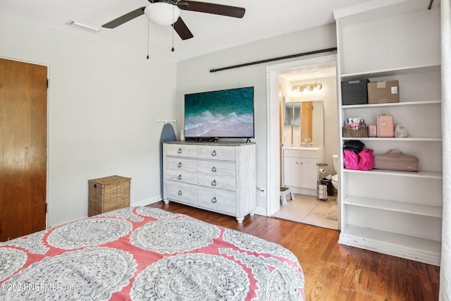 bedroom with hardwood / wood-style flooring, connected bathroom, and ceiling fan