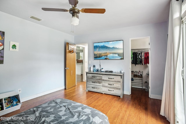 bedroom featuring a spacious closet, a closet, light hardwood / wood-style floors, and ceiling fan