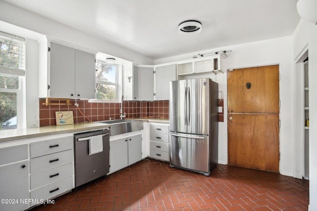 kitchen with sink, appliances with stainless steel finishes, a wealth of natural light, and decorative backsplash