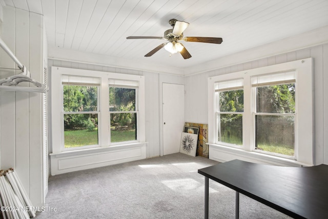 unfurnished sunroom featuring ceiling fan, wooden ceiling, and plenty of natural light