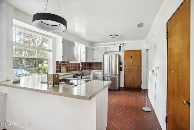 kitchen featuring appliances with stainless steel finishes, kitchen peninsula, sink, and backsplash