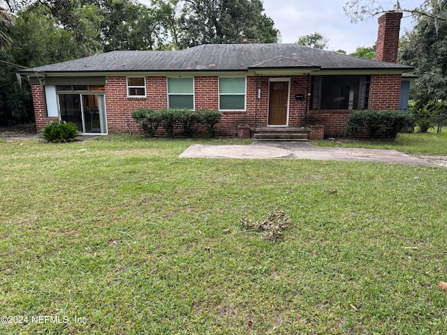 ranch-style house featuring a front lawn and a patio