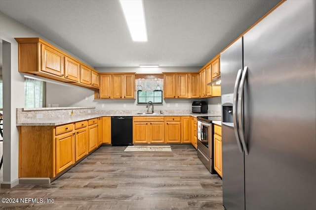 kitchen featuring light hardwood / wood-style floors, appliances with stainless steel finishes, sink, and a textured ceiling