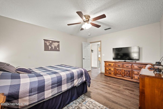 bedroom with a textured ceiling, hardwood / wood-style floors, and ceiling fan