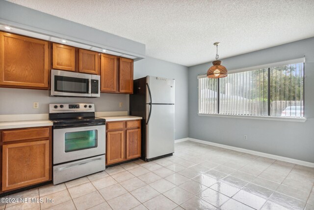 kitchen with light tile patterned floors, refrigerator, white electric stove, pendant lighting, and a textured ceiling