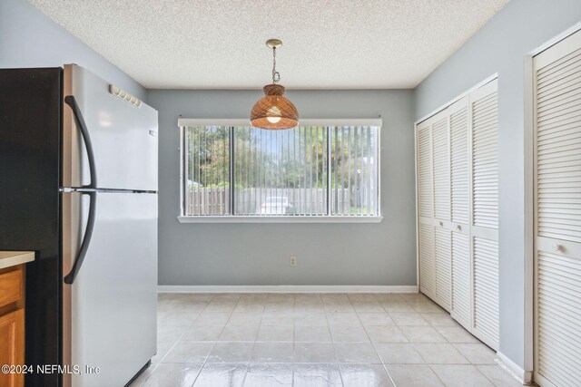 kitchen with decorative light fixtures, light tile patterned flooring, stainless steel refrigerator, and a textured ceiling