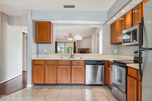 kitchen with light tile patterned floors, a textured ceiling, stainless steel appliances, and sink