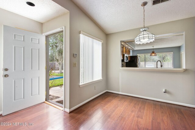 foyer entrance with hardwood / wood-style flooring, plenty of natural light, and a textured ceiling