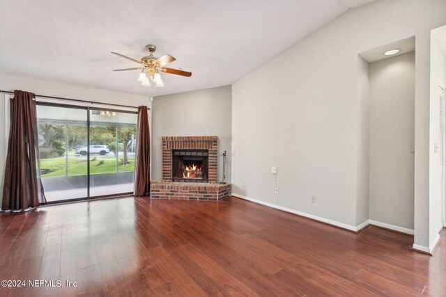 unfurnished living room featuring dark hardwood / wood-style flooring, a brick fireplace, and ceiling fan