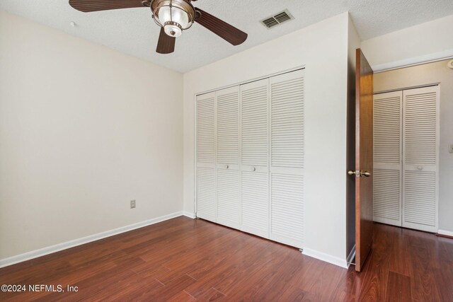 unfurnished bedroom featuring a textured ceiling, ceiling fan, dark hardwood / wood-style floors, and a closet