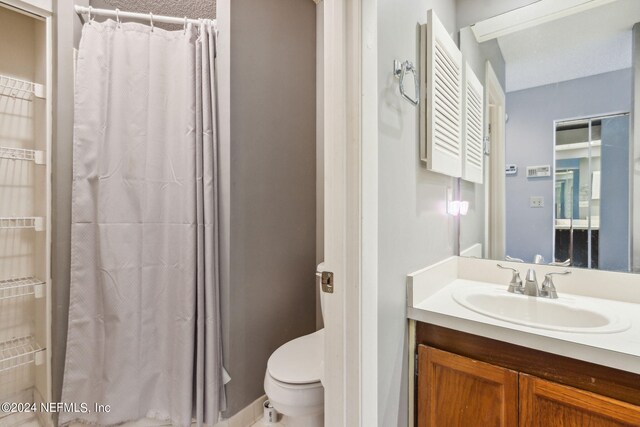 bathroom featuring a shower with shower curtain, toilet, and vanity