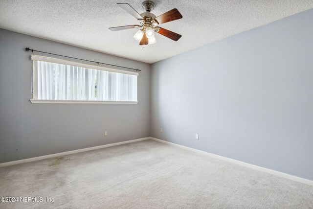 spare room with a textured ceiling, ceiling fan, and carpet