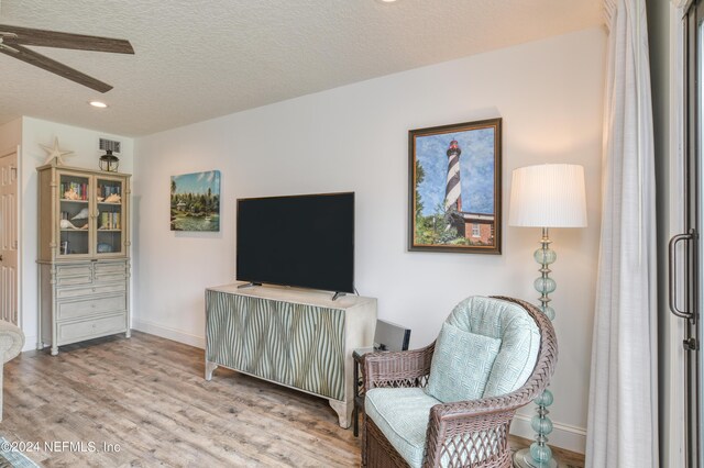 sitting room with a textured ceiling, light hardwood / wood-style flooring, and ceiling fan